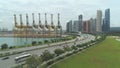 AERIAL: Cars on turnpike road driving past large cranes and soaring skyscrapers.