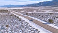 AERIAL: Cinematic shot of a silver SUV driving across the wintry landscape.