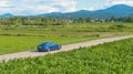 AERIAL: Cinematic shot of a new Tesla Model 3 driving itself down a scenic road.