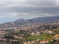 Aerial cityscape view of the outskirts of funchal in Madeira with farms and houses with mountains and cloudy sky in the distance