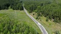 Aerial. Commercial truck leaves the forest terrain. View above from drone