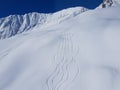 AERIAL: Cool shot of snowboarder and skier trails running down snowy mountain. Royalty Free Stock Photo