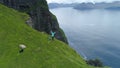 AERIAL: Cheerful woman standing on the edge of a cliff with outstretched arms. Royalty Free Stock Photo