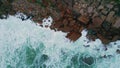 Aerial dark rough coast washed foamy ocean water. Waves crashing of rocky shore Royalty Free Stock Photo