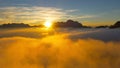 AERIAL: Clouds gather over the valley as golden evening sun shines on mountains. Royalty Free Stock Photo