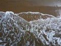Aerial down view of whit waves washing on the beach
