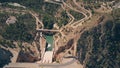 Aerial down view of windy hairpinned car road and dam in mountains in Spain