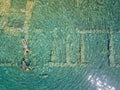 Aerial drone bird`s eye view photo of tourists snorkeling above old Sunken City of Epidauros, Greece