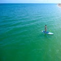 Aerial drone birds eye view of young woman exercising sup board in turquoise tropical clear waters Royalty Free Stock Photo