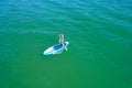 Aerial drone birds eye view of young woman exercising sup board in turquoise tropical clear waters Royalty Free Stock Photo