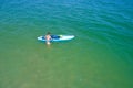 Aerial drone birds eye view of young woman exercising sup board in turquoise tropical clear waters Royalty Free Stock Photo