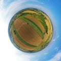 Aerial drone 360 degree spherical tiny planet view on red harvester during wheat field harvesting, collecting seeds, making dust