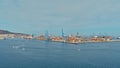 aerial drone image of the harbor with numerous containers piled up next to cranes ans a small sailing dinghy race