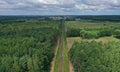 Aerial drone perspective view on straight railroad in rural scenery with green forest during summer