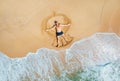 drone photo of a man lying on the sandy ocean shore and making butterfly and sun tanning. waves washed his legs on