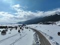 Aerial, drone shot over leafless trees, above a snowy mountain and beautiful snowy mountain peaks. Winter wilderness, on Royalty Free Stock Photo