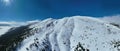 Aerial, drone shot over leafless trees, above a snowy mountain and beautiful snowy mountain peaks. Winter wilderness, on Royalty Free Stock Photo