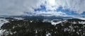 Aerial, drone shot over leafless trees, above a snowy mountain and beautiful snowy mountain peaks. Winter wilderness, on Royalty Free Stock Photo