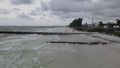 Aerial drone shot traveling over water towards jetty and dock looking down a coastline