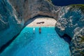 Aerial drone shot of Zakynthos Navagio beach with tourists with cruise ship in blue Ionnian sea