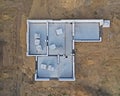 Aerial drone top down view on construction site with reinforced concrete house foundation, poured concrete floor and brick walls