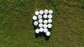 Aerial drone top down view on green meadow with foiled hay round bales stored for future use