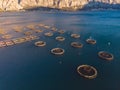 Aerial drone top view of sea fish farm cages and fishing nets, farming dorado, sea bream and sea bass, feeding the fish a forage,