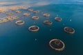 Aerial drone top view of sea fish farm cages and fishing nets, farming dorado, sea bream and sea bass, feeding the fish a forage,