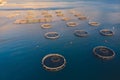 Aerial drone top view of sea fish farm cages and fishing nets, farming dorado, sea bream and sea bass, feeding the fish a forage,