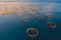 Aerial drone top view of sea fish farm cages and fishing nets, farming dorado, sea bream and sea bass, feeding the fish a forage,