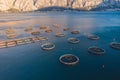Aerial drone top view of sea fish farm cages and fishing nets, farming dorado, sea bream and sea bass, feeding the fish a forage,