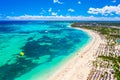 Aerial drone view of beautiful atlantic tropical beach with palms, straw umbrellas and boats. Bavaro, Punta Cana, Dominican