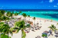 Aerial drone view of beautiful atlantic tropical beach with palms, straw umbrellas and boats. Bavaro, Punta Cana, Dominican