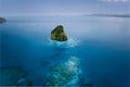 Aerial drone view of a beautiful secluded surreal cliff island surrounded by azure turquoise blue ocean water. Bacuit