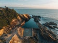 Aerial drone view of Blue Pool in Bermagui during sunrise sunset with blue sky and reflection. New South Wales