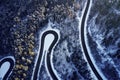 Aerial drone view of a curved winding road through the forest high up in the mountains in the winter with snow covered Royalty Free Stock Photo