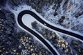 Aerial drone view of a curved winding road through the forest high up in the mountains in the winter with snow covered Royalty Free Stock Photo