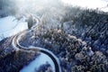 Aerial drone view of a curved winding road through the forest up in the mountains in the winter with snow covered trees Royalty Free Stock Photo