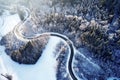 Aerial drone view of a curved winding road through the forest up in the mountains in the winter with snow covered trees Royalty Free Stock Photo