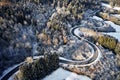 Aerial drone view of a curved winding road through the forest up in the mountains in the winter with snow covered trees Royalty Free Stock Photo