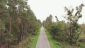 Aerial drone view of empty car asphalt road in green pine forest. Cyclist rides on road bike in forest. Person is cycling on bicyc