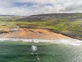 Aerial drone view on Fanore beach, county Clare, Ireland. Warm sunny day, People on the beach and surfing in the water. Cloudy sky Royalty Free Stock Photo