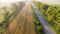 Aerial drone view flight over highway, wheat field and green trees at sunset Royalty Free Stock Photo