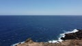 Aerial drone view of foamy waves crashing on a rocky coast on a sunny day in Tenerife Royalty Free Stock Photo