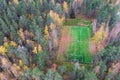 Aerial drone view of football soccer pitch field, green grass fall autumn vibrant pitch playground with fallen multicolored leaves