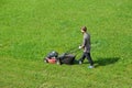 Aerial drone view of gardener mowing green grass lawn with motorized lawnmower in the garden. Landscaping service, gardening Royalty Free Stock Photo