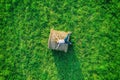 Aerial drone view of happy smiling girl with jeans resting on hay bale and green grass meadow