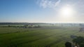 Aerial drone view high up to the sun rising and shining over beds of green ripening potatoes bushes. Country field of Royalty Free Stock Photo