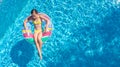 Aerial drone view of little girl in swimming pool from above, kid swims on inflatable ring donut , child has fun in blue water Royalty Free Stock Photo
