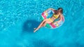 Aerial drone view of little girl in swimming pool from above, kid swims on inflatable ring donut , child has fun in blue water Royalty Free Stock Photo